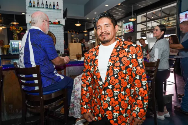 A man in an orange pumpkin-print blazer standing at the bar