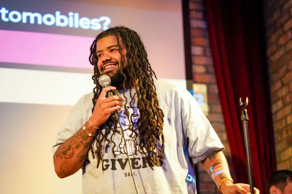 A close-up of a smiling comedian speaking into the microphone