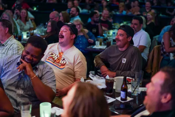 Audience members laughing hard at their tables